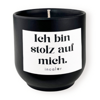 Freigestellte Kerze aus dunkler Keramik (Farbton basalt) mit Etikett der Affirmation "Ich bin stolz auf mich." – stilvolle Designkerze von incalor für Achtsamkeit, Selbstmotivation und modernes Interior.