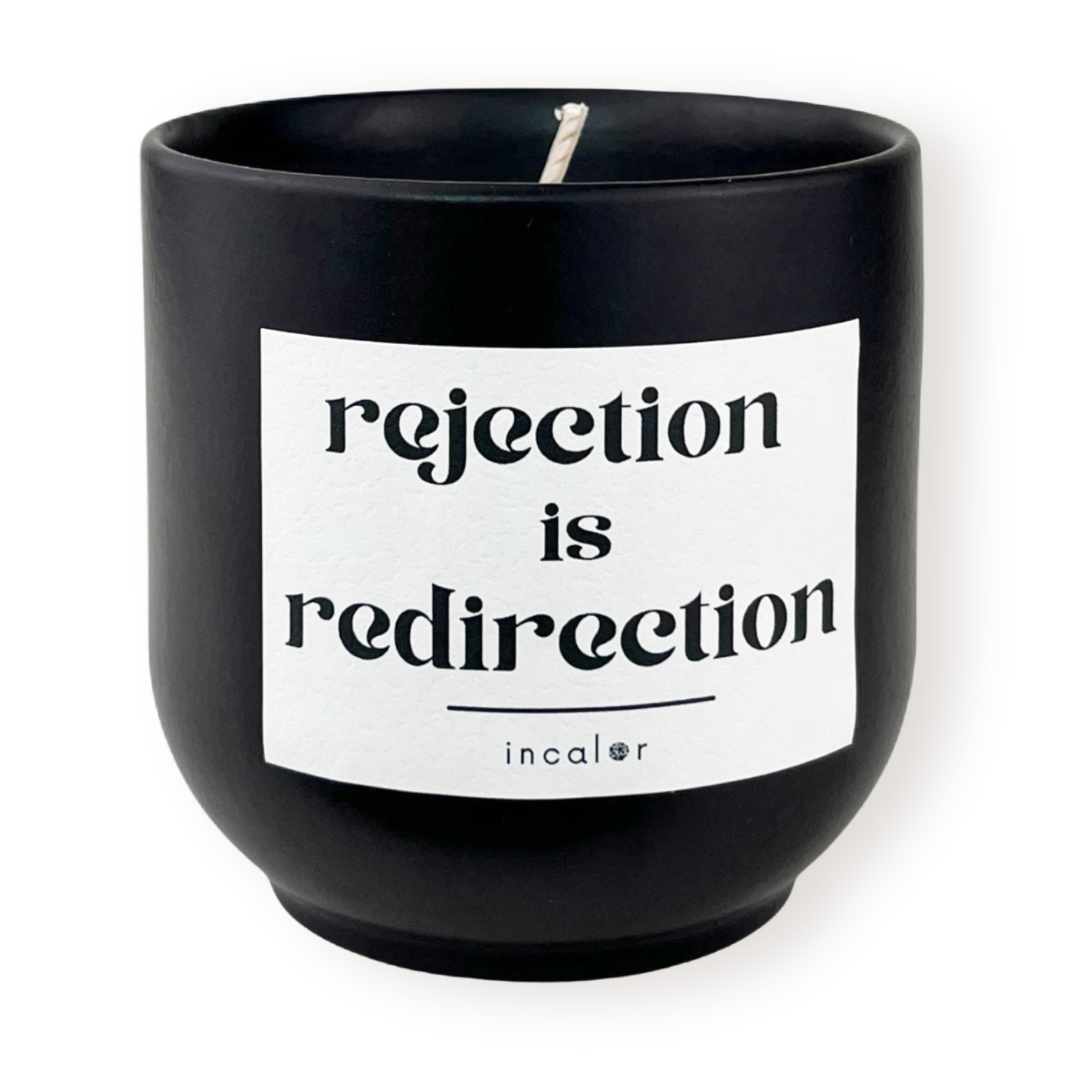 Freigestellte Kerze aus dunkler Keramik (Farbton basalt) mit Etikett der Affirmation "rejection is redirection." – stilvolle Designkerze von incalor für Achtsamkeit, Selbstmotivation und modernes Interior.