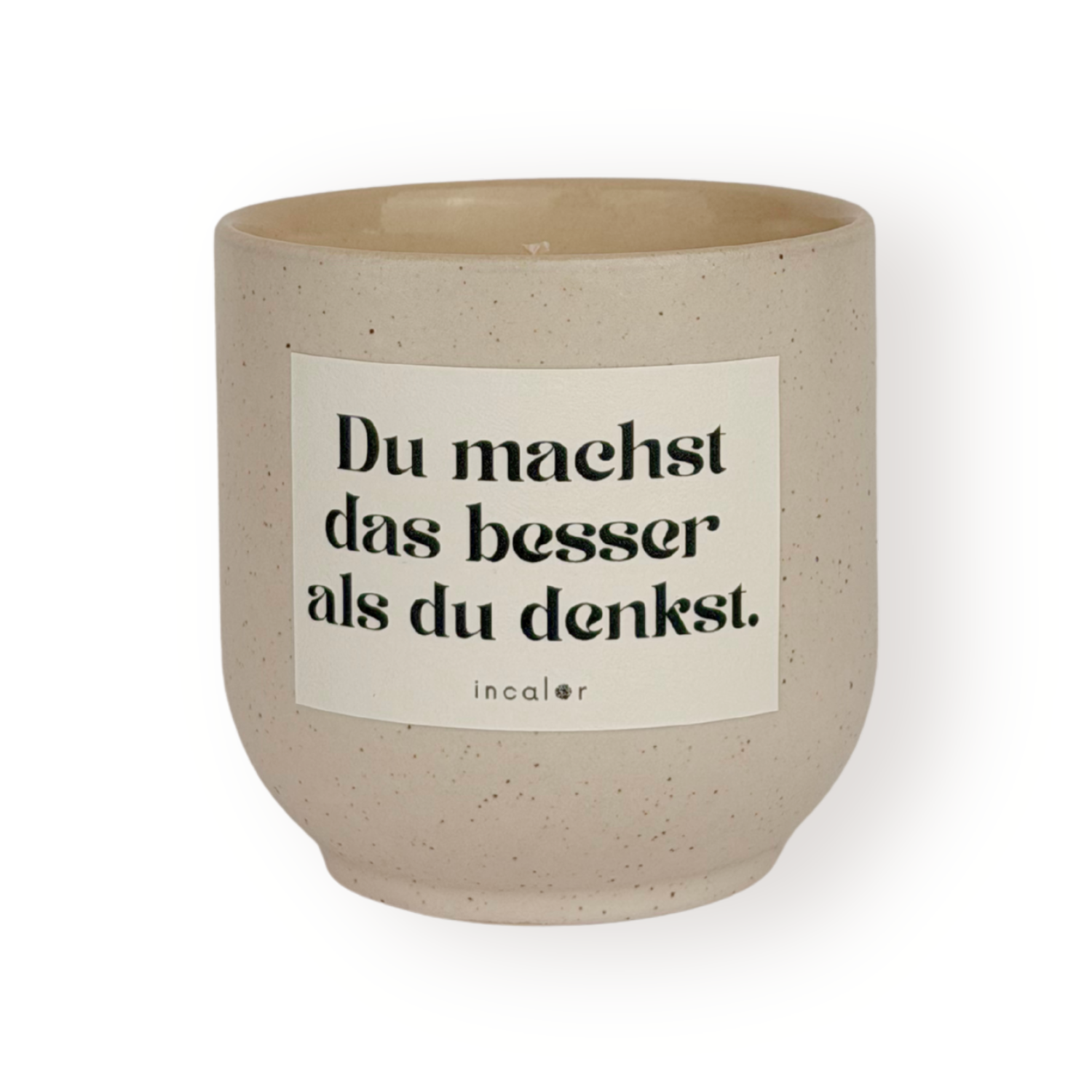 Beige Duftkerze (sahara) mit dezent gesprenkelter Oberfläche und weißem Etikett mit der Aufschrift „Du machst das besser als du denkst.“ von incalor, freigestellt vor weißem Hintergrund 