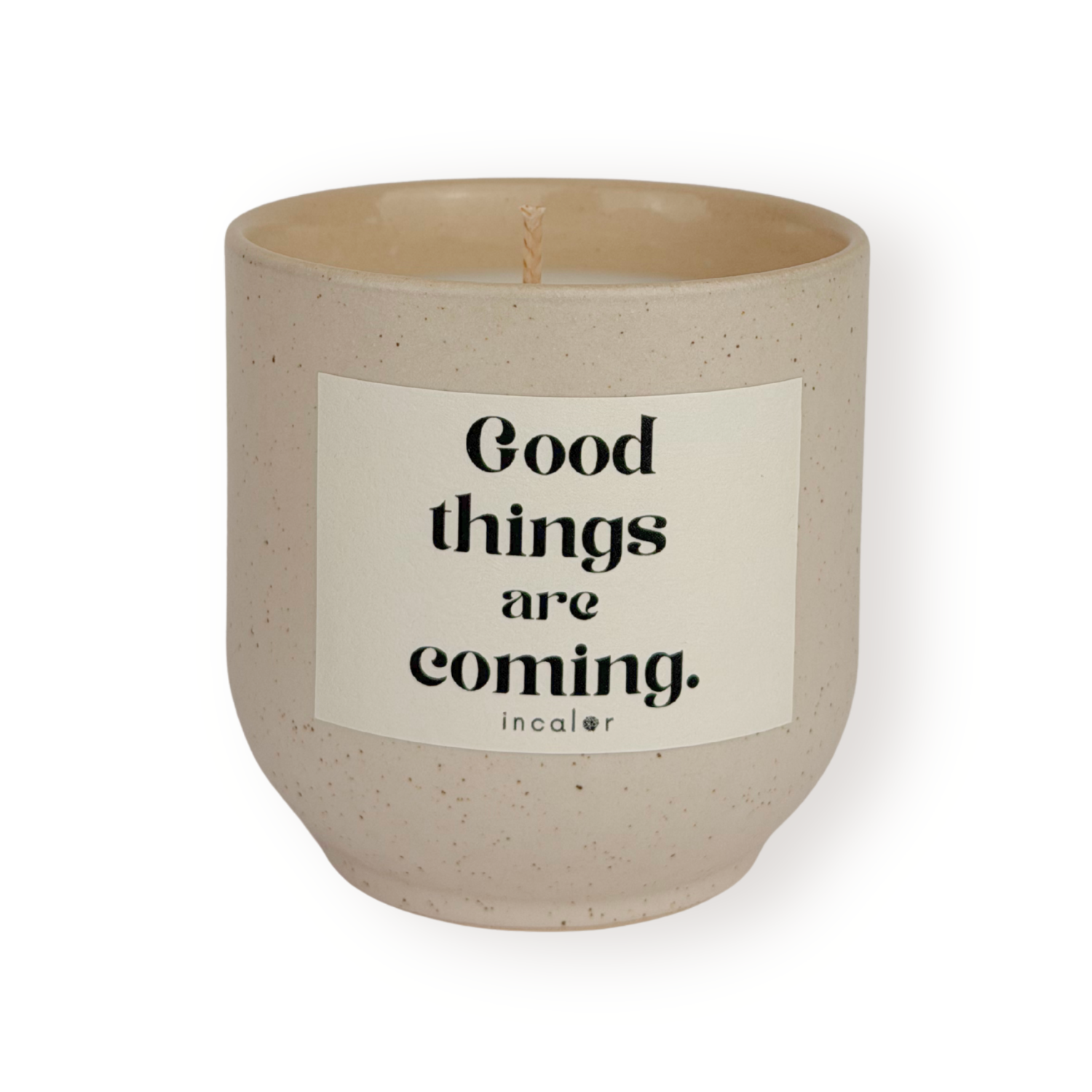 Beige Duftkerze (sahara) mit dezent gesprenkelter Oberfläche und weißem Etikett mit der Aufschrift „Good things are coming.“ von incalor, freigestellt vor weißem Hintergrund 