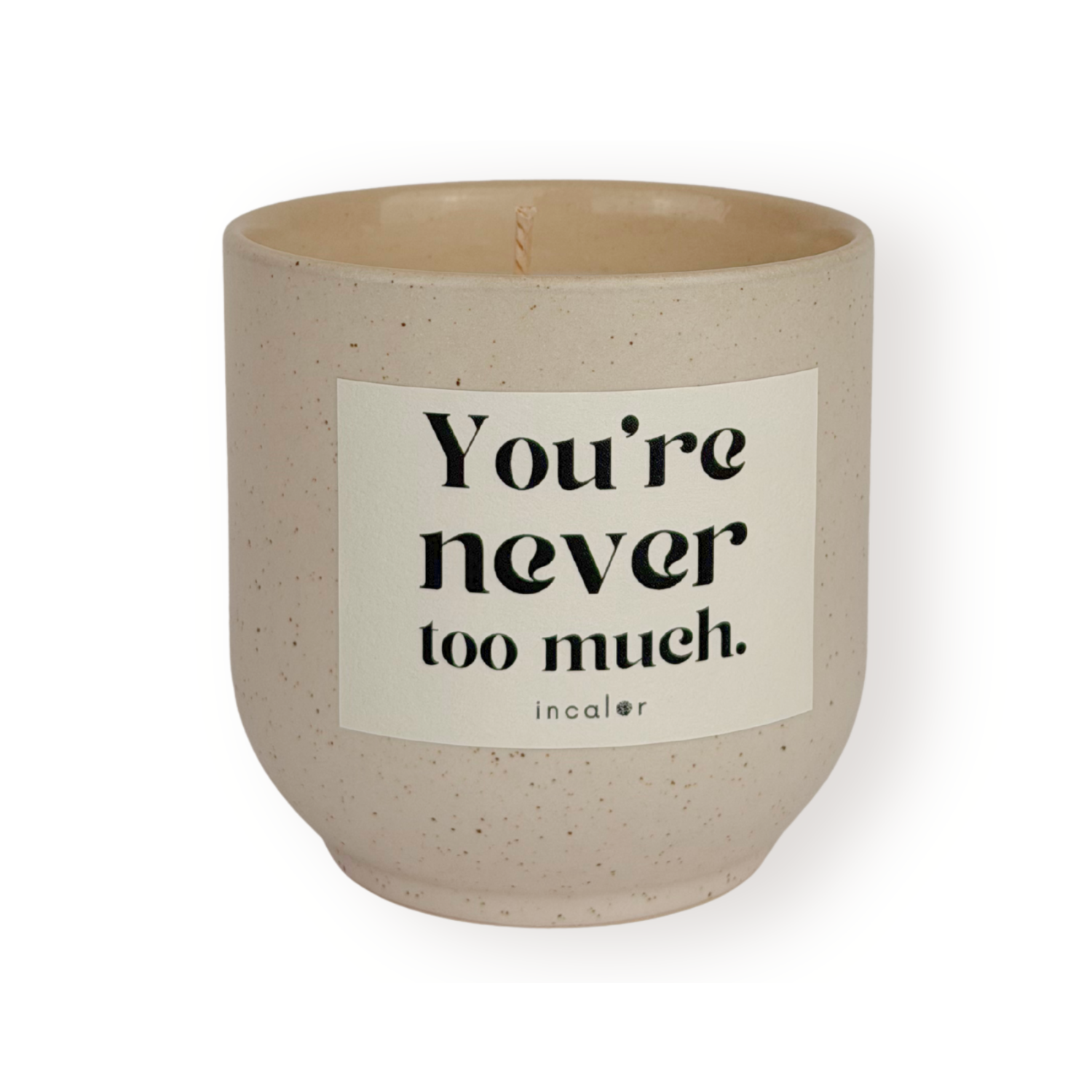Beige Duftkerze (sahara) mit dezent gesprenkelter Oberfläche und weißem Etikett mit der Aufschrift „You're never too much.“ von incalor, freigestellt vor weißem Hintergrund 