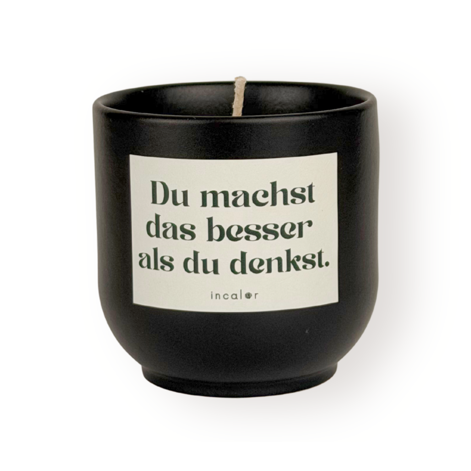 Schwarze (basalt) Duftkerze mit weißem Etikett und der Aufschrift „Du machst das besser als du denkst.“ sowie dem Markennamen „incalor“ darunter; freigestellt vor weißem Hintergrund