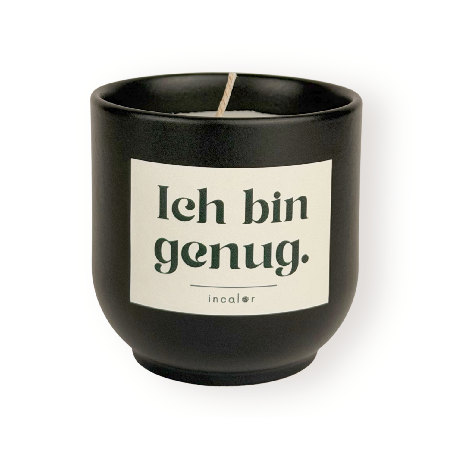 Schwarze (basalt) Duftkerze mit weißem Etikett und der Aufschrift „Ich bin genug.“ sowie dem Markennamen „incalor“ darunter; freigestellt vor weißem Hintergrund