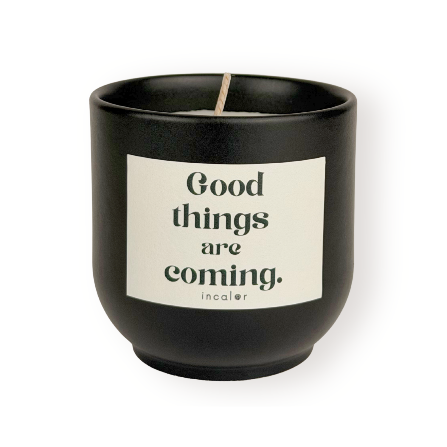 Schwarze (basalt) Duftkerze mit weißem Etikett und der Aufschrift „Good things are coming.“ sowie dem Markennamen „incalor“ darunter; freigestellt vor weißem Hintergrund