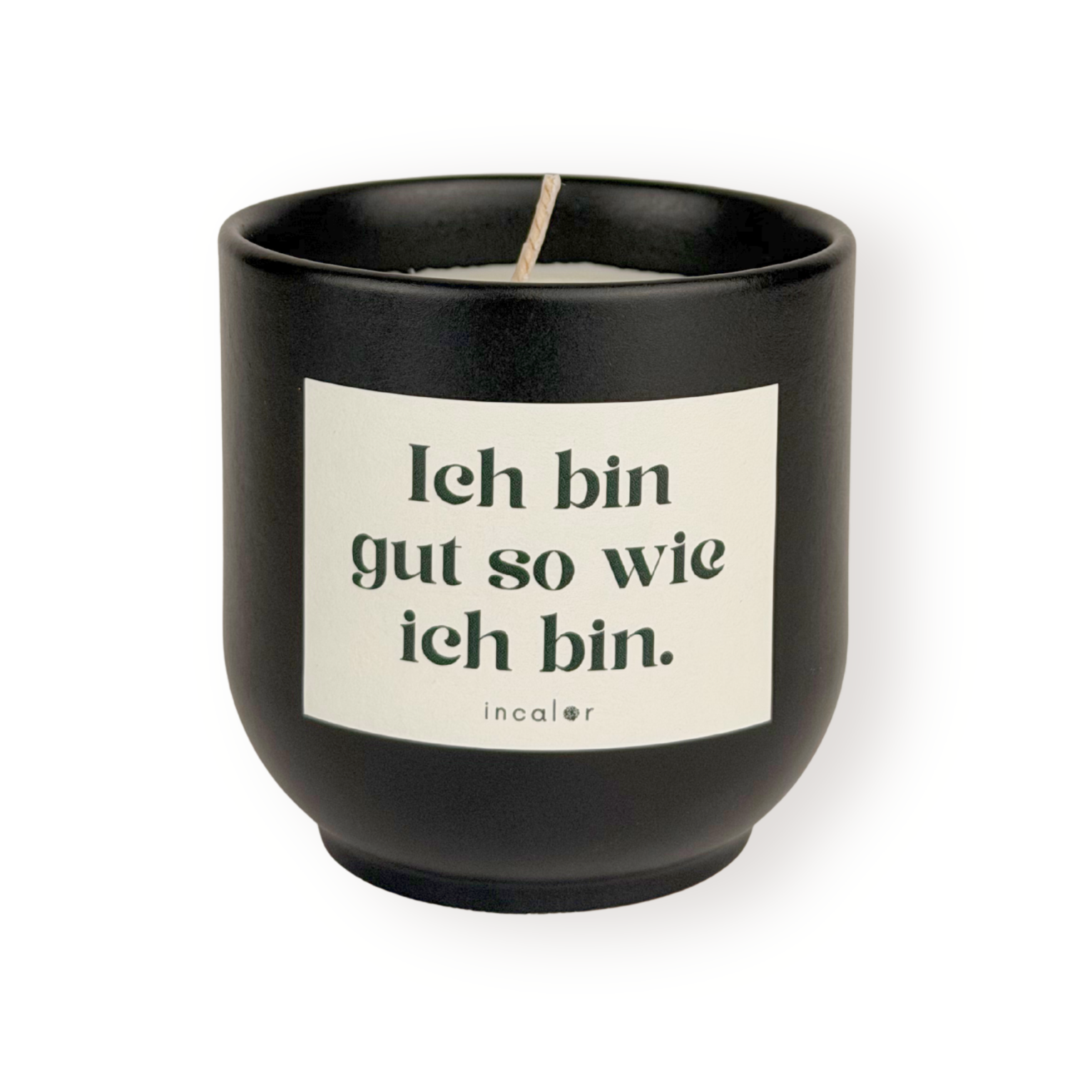 Schwarze (basalt) Duftkerze mit weißem Etikett und der Aufschrift „Ich bin gut so wie ich bin.“ sowie dem Markennamen „incalor“ darunter; freigestellt vor weißem Hintergrund