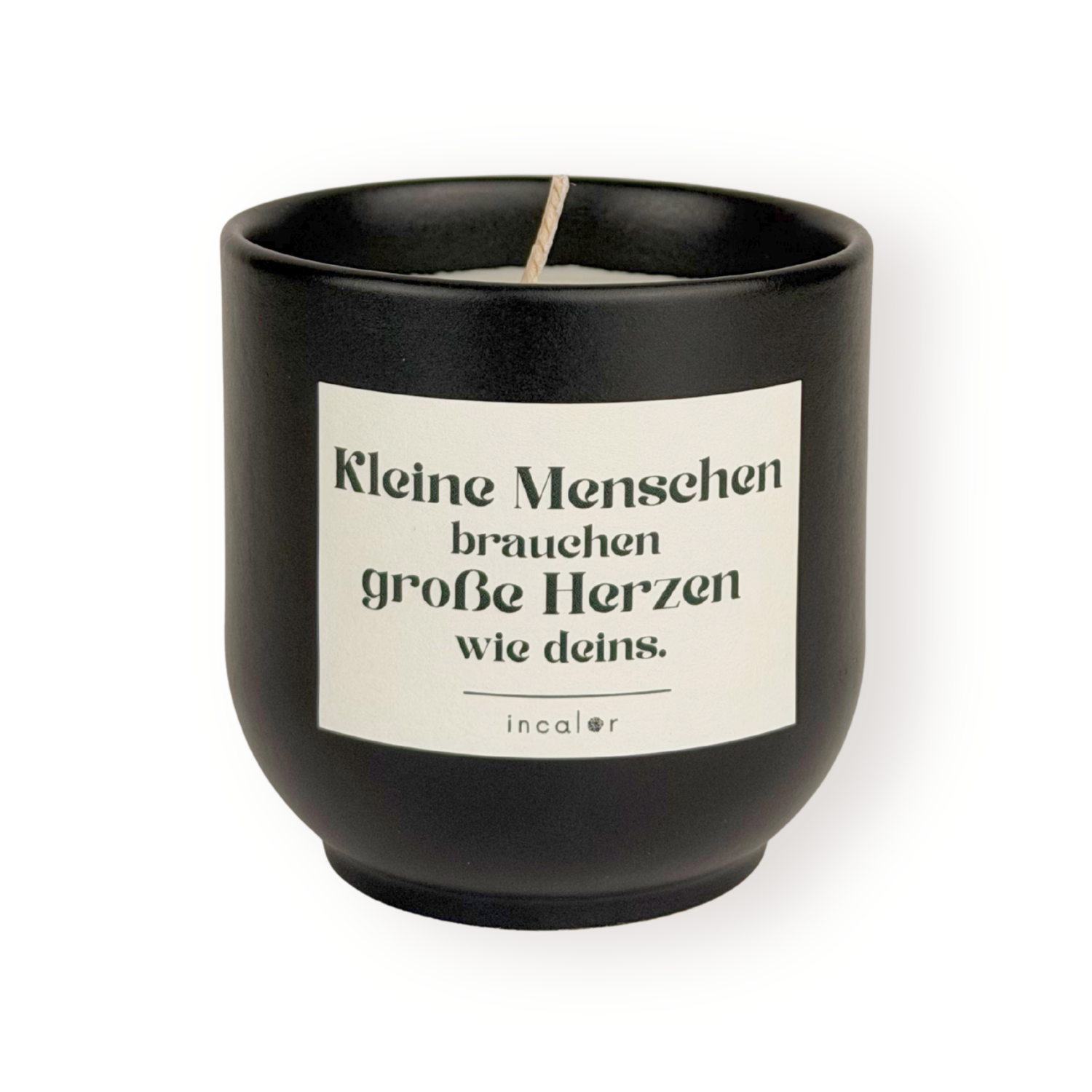 Schwarze (basalt) Duftkerze mit weißem Etikett und der Aufschrift „Kleine Menschen brauchen große Herzen wie deins.“ sowie dem Markennamen „incalor“ darunter; freigestellt vor weißem Hintergrund