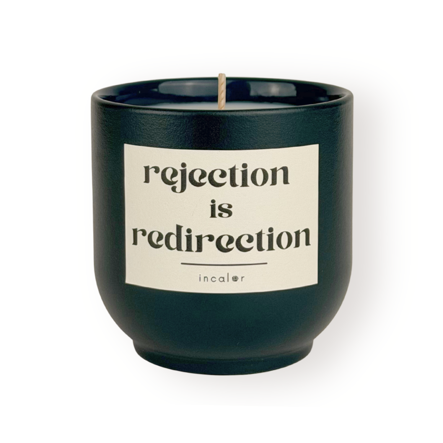Dunkelgrüne Duftkerze (deep ivy) mit cremefarbenem Etikett vor weißem Hintergrund. Auf dem Etikett steht in schwarzer Schrift: "rejection is redirection". Darunter befindet sich das Markenlogo "incalor". Die Kerze ist mittig platziert und gleichmäßig ausgeleuchtet.